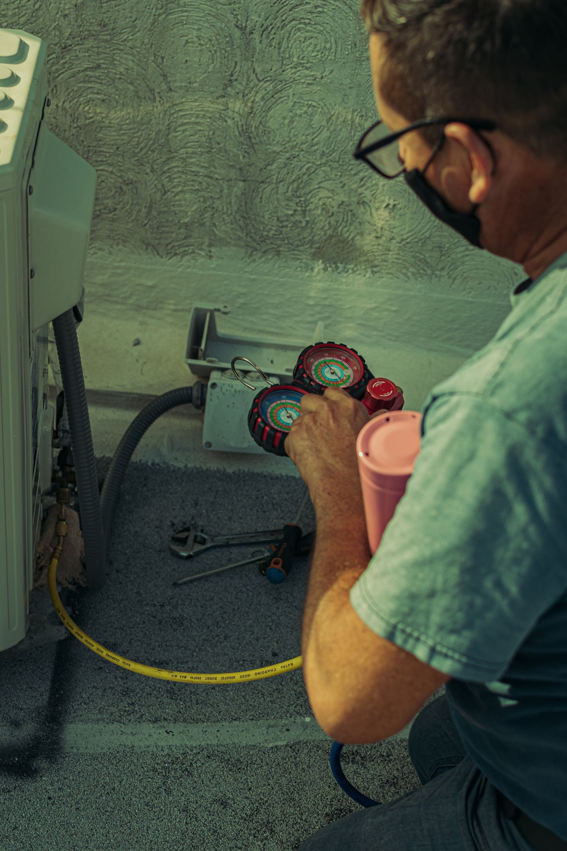 Technician checking an outdoor HVAC system with pressure gauges